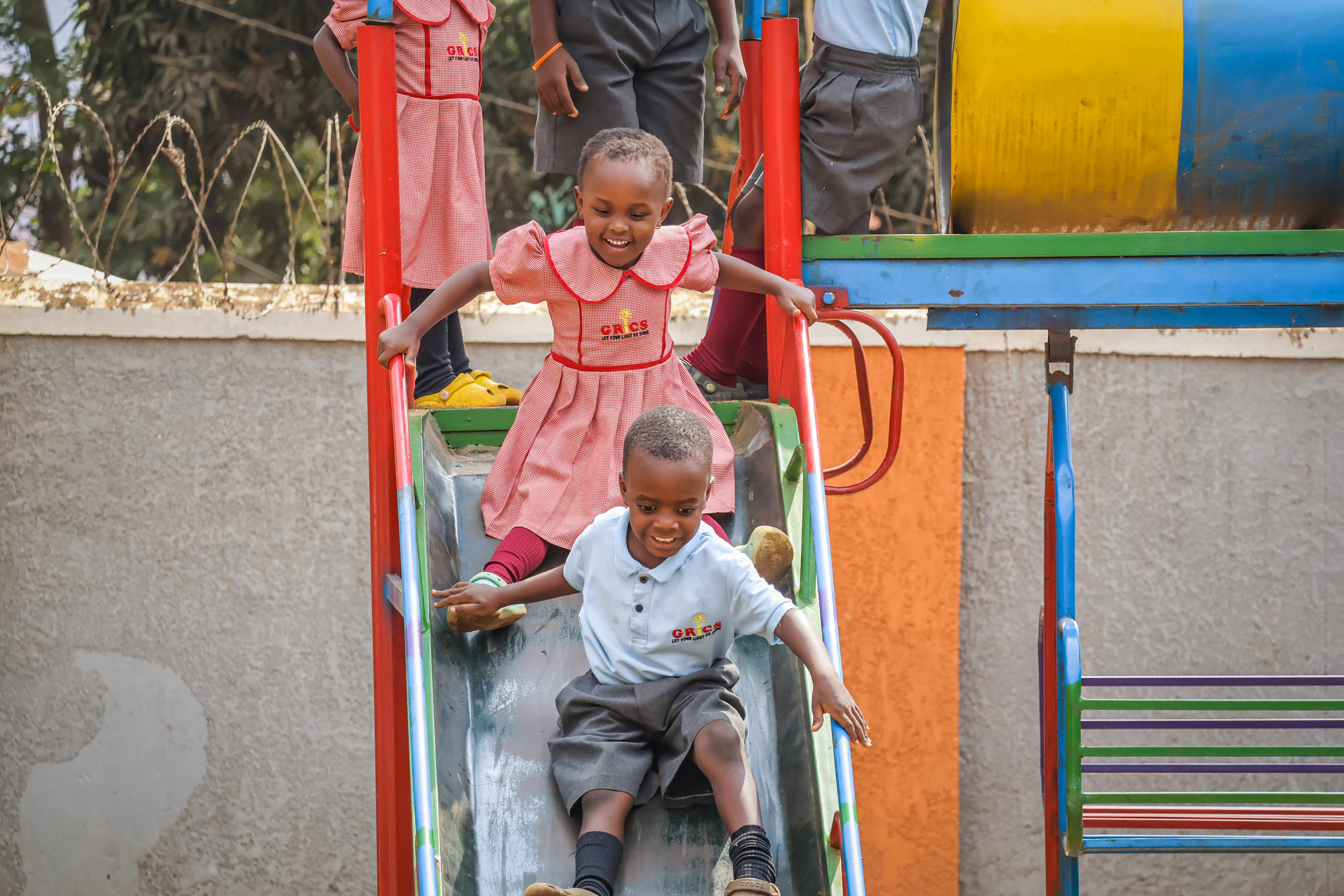 Two students sliding down the playground slide together